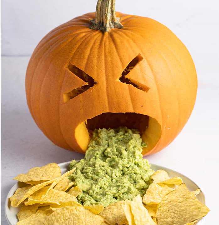 Photo of a jack-o-lantern throwing up guacamole into a plate of tortilla chips